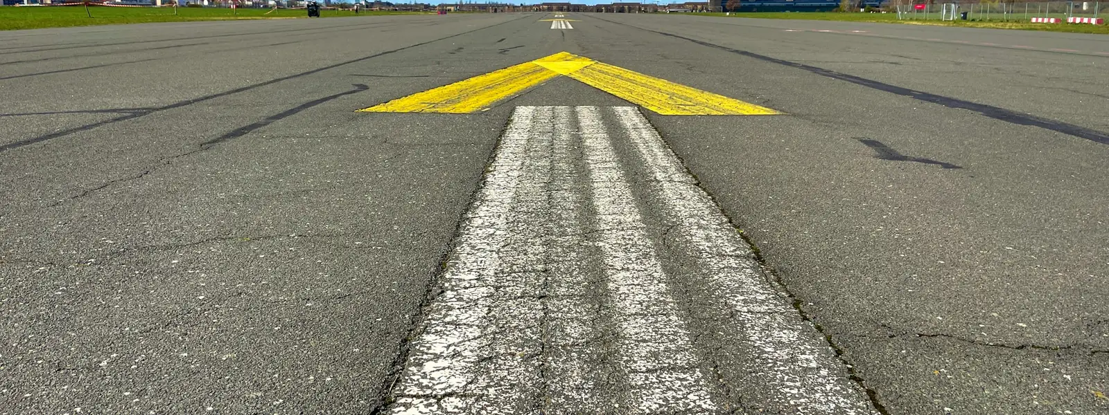 Runway markings on an airfield under a bright blue sky