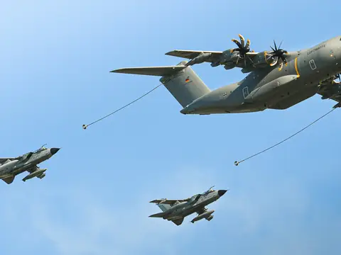 Military transport aircraft flying above two fighter jets